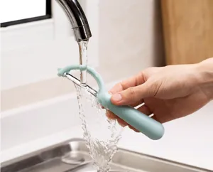 Vue détaillée d'un économe de cuisine pour fruits et légumes rincé sous l'eau courante.