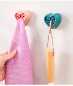 Close-up detail of wall-mounted heart-shaped silicone towel holder plug for home bathroom kitchen.