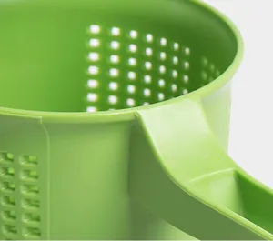 Detalle colador de verduras manual de plástico verde, prensa de agua y drenaje de cocina