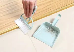 Mini desktop broom dustpan set detail showing hand cleaning small gap and dust efficiently.