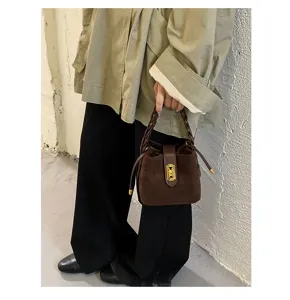 Borsa a secchiello in camoscio marrone da donna, elegante manico intrecciato con serratura.