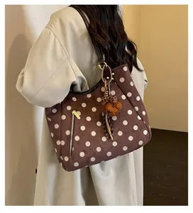 Detailansicht der braunen Wildleder-Polka-Dot-Tasche mit süßem Bärenanhänger und Reißverschlusstasche.