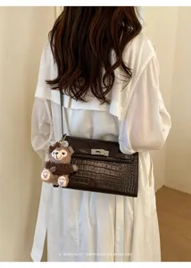 Elegant dark brown crocodile pattern shoulder bag with retro Kelly design and cute bear charm.