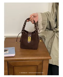 Borsa a secchiello in camoscio marrone stile Maillard con manico intrecciato e chiusura chic.