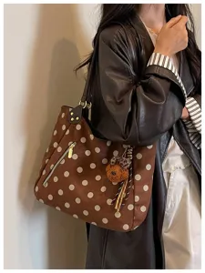 Detailaufnahme einer braunen Wildleder-Punkte-Tasche mit Bärenanhänger für Herbststil Damen.