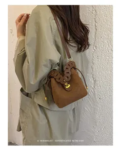 Borsa a secchiello in camoscio marrone stile Maillard con manico intrecciato e chiusura.