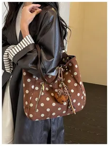 Nahaufnahme der braunen Wildleder Pünktchen Tasche mit weichem Material und süßem Bärenanhänger.