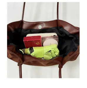 Bruine sude tote bag binnendetail met grote capaciteit voor dagelijks woon-werkverkeer.