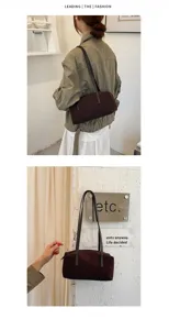 Vue détaillée du sac porté épaule bowling en daim marron au design rétro épuré et fines brides.
