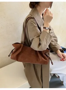 Bruine suède schoudertas detailweergave, zachte tekstuur, trekkoordontwerp, chique stijl.