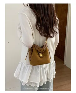 Borsa a secchiello in scamosciato chic con manico intrecciato e chiusura per stile retro.