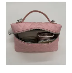 Détail intérieur de trousse de toilette matelassée rose avec espace de rangement et cosmétiques