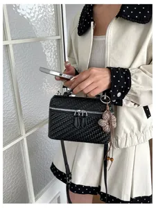 Detailed shot of a stylish black woven box handbag, showcasing texture and crossbody strap.