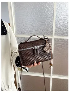 Detailed close-up view of retro woven brown vanity bag featuring cute floral tassel charm and zipper.