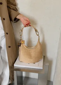Sac hobo souple en suédine beige avec charm fleur, élégant sac porté épaule pour femme chic.