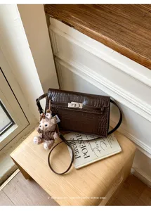 Stylish brown crocodile pattern shoulder bag with cute plush bear pendant.