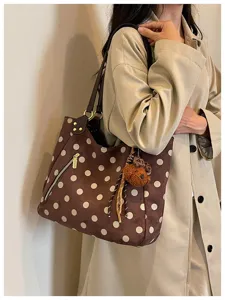 Detailaufnahme einer retro braunen Wildleder Pünktchen Tasche mit süßem Plüsch Bär Anhänger.