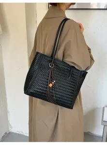 Black woven tote bag for women, stylish leather shoulder bag with tassel charm, large capacity.