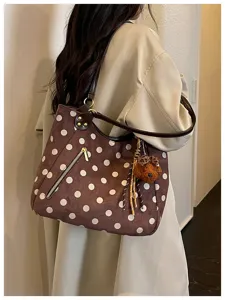 Detailaufnahme der eleganten braunen Wildleder-Punkte-Tasche mit süßem Bärenanhänger.