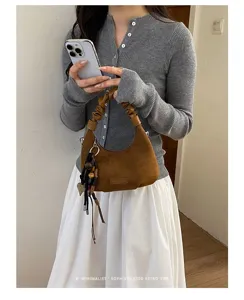 Vue détaillée du sac porté épaule rétro en suédine pour femmes avec charmant pompon élégant.