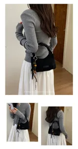 Détails du sac porté épaule en suédine noire avec poignée froncée et charmant pompon élégant.
