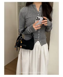 Détail du sac porté épaule en suédine noire avec pendentifs perlés au style rétro chic.