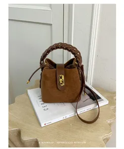 Borsa a secchiello in camoscio marrone con manico intrecciato, chiusura dorata e tracolla.