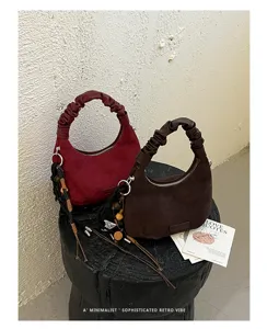 Vue détaillée de sacs à main en suède élégants avec poignées froncées et pampilles.