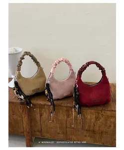 Vue détaillée de sacs à épaule élégants en suédine avec anses plissées et charmants pendentifs.