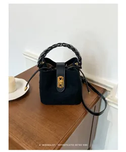 Primo piano dettagliato di una borsa a secchiello in camoscio nero con manico intrecciato.