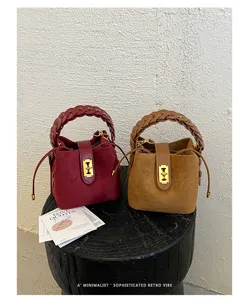 Borsa a secchiello in camoscio chic con manico intrecciato e dettaglio dorato rétro.