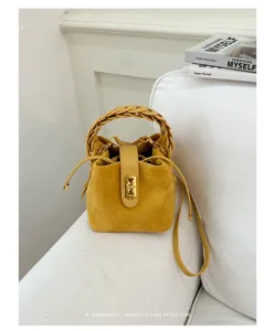 Borsa a secchiello in camoscio giallo con manico intrecciato e chiusura dorata chic.