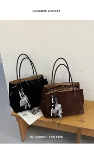 Detail van grote suède shopper tassen met dubbele handvatten en chique bedels.