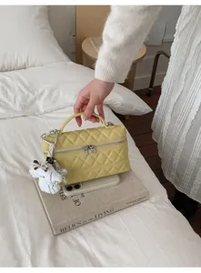 Sac à main matelassé chic avec poignée supérieure et charmant pendentif en peluche.