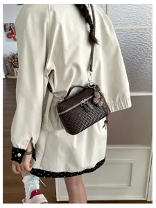 Retro woven lunch box bag detail view, showing exquisite dark brown texture and chic tassel charm.