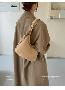 Vue détaillée du sac hobo en daim rétro montrant son design souple et son charmant pendentif.