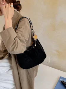 Vue détaillée du sac porté épaule hobo en suédine noire avec charm fleur, style chic.