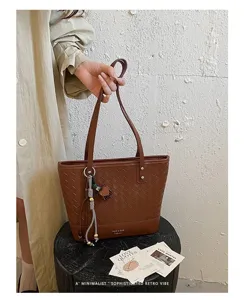 Detail van bruine geweven tote bag met prachtig vlechtpatroon en stijlvolle tashanger.