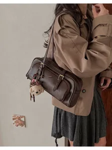 Brown vintage baguette shoulder bag detail showing leather texture and cute bear charm.