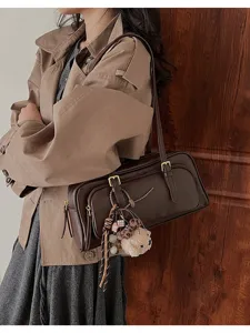Brown leather baguette shoulder bag detail view with cute plush bear pendant and chic style.