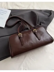 Detailed view of dark brown leather baguette shoulder bag with stylish double buckle straps.