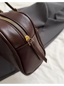 Brown leather baguette bag detail view, stylish minimalist women underarm shoulder handbag.