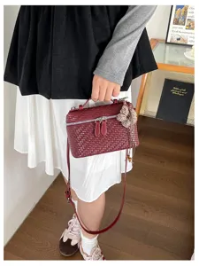 Woven box handbag detail view, vintage burgundy top handle bag with stylish tassel pendant.