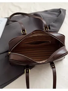 Brown leather shoulder tote bag interior detail, striped lining with zipper pocket and metal buckles.