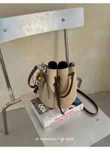 Detailaufnahme der Retros Wildleder-Beuteltasche mit Kordelzug und Blumenanhänger auf Stuhl.