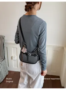 Vista di dettaglio di borsa a spalla strutturata ed elegante con ciondolo floreale lavorato.