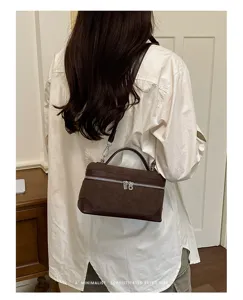 Detail view of retro suede vanity box bag with top handle and shoulder strap in brown color.