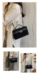 Minimalist black retro vanity shoulder bag detail, stylish suede texture with metallic zippers.