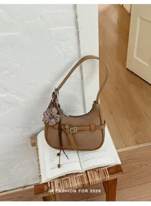 Vista dettagliata della borsa a spalla intrecciata marrone con ciondolo floreale e cinturino.