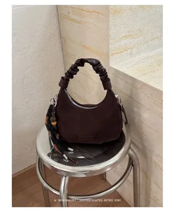 Vue détaillée du sac porté épaule en daim marron avec poignée froncée et charme.